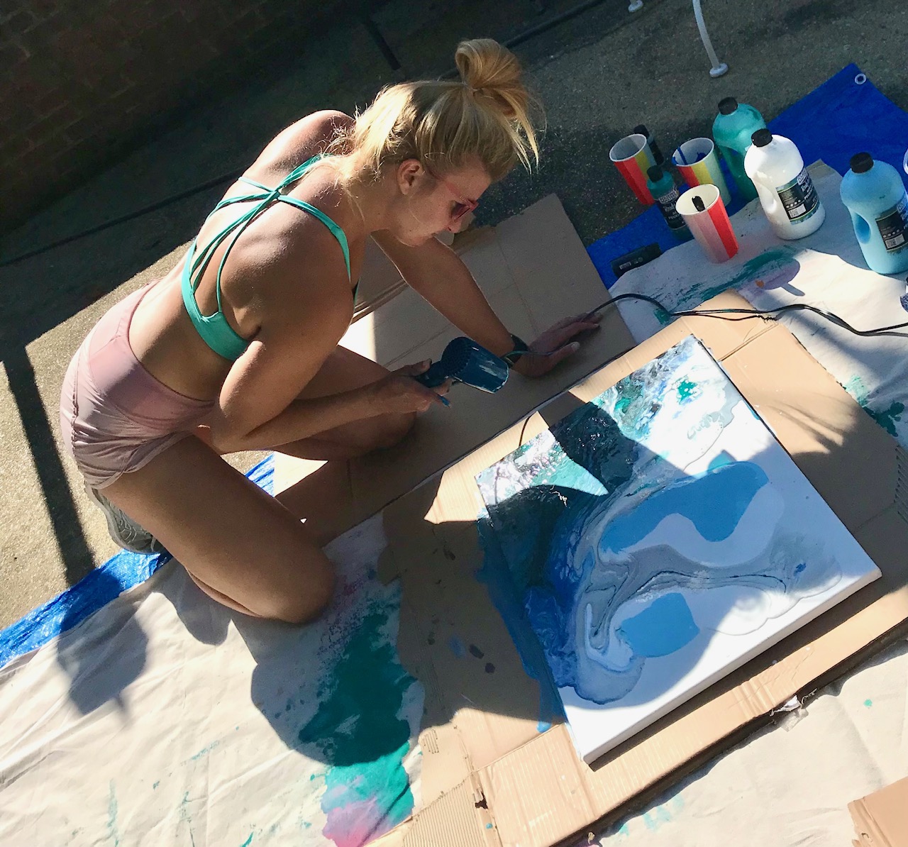 Danielle Eze pouring and heat-setting paint on a canvas outdoors