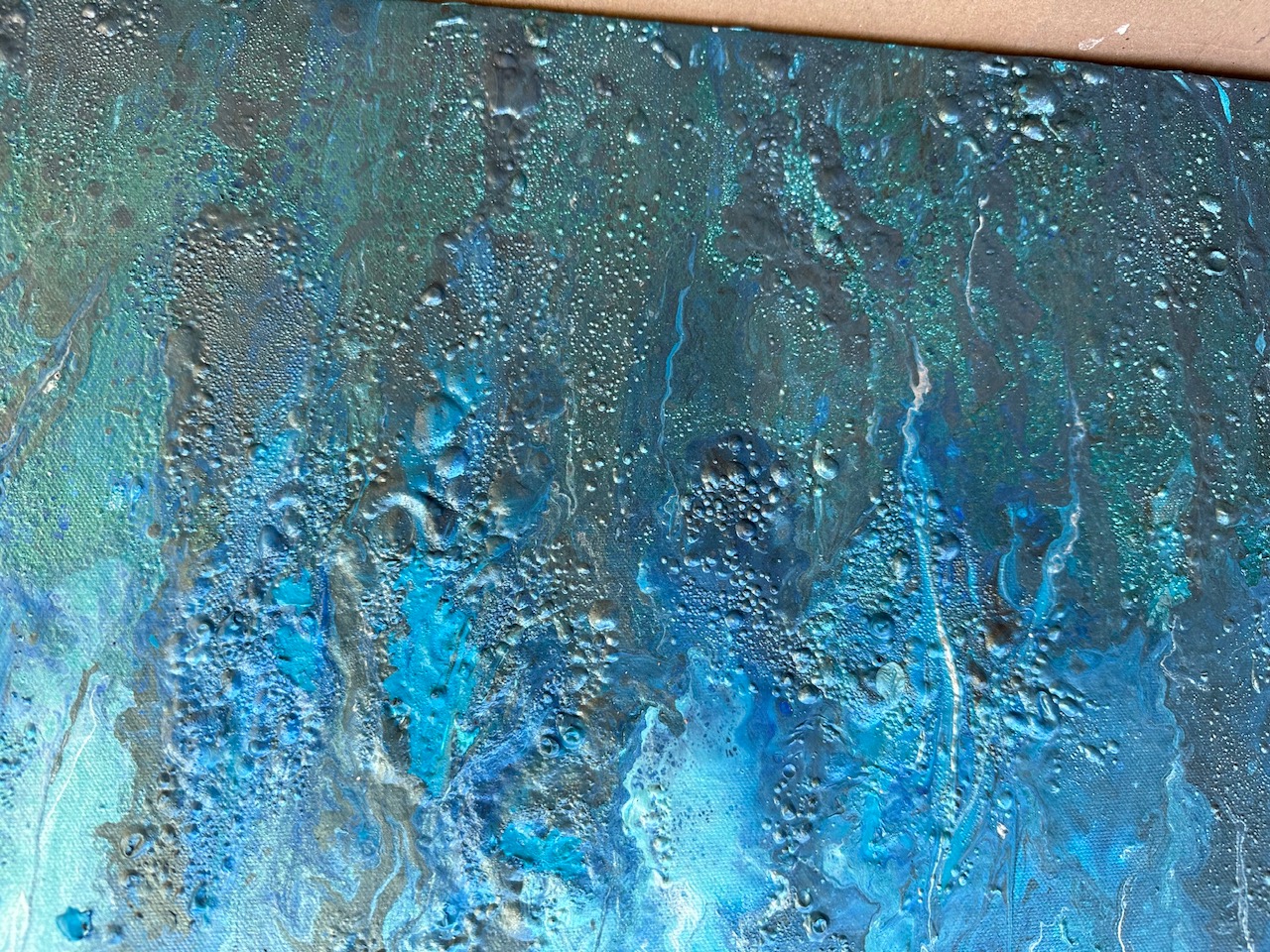 Close-up of aqua pigment falling in vertical ribbons